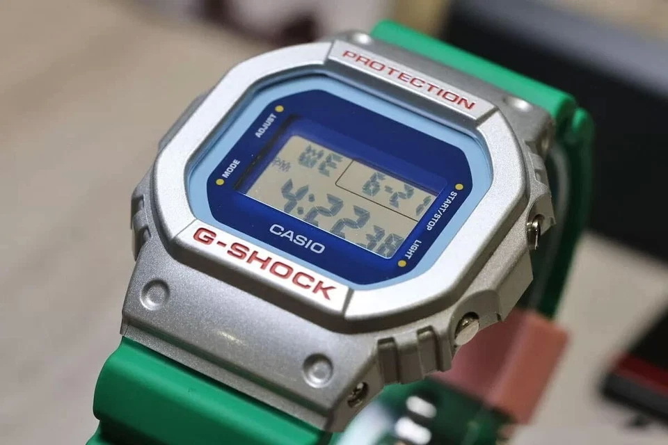 DW-5600EU-8A3D-7 ساعت مچی دیجیتال مردانه Casio G‑SHOCK DW‑5600EU‑8A3D با قاب طوسی روشن مات، بند رزین روشن، طراحی مربعی کلاسیک، مقاومت ضربه، نور پسزمینه EL و مقاومت آب ۲۰۰ متر مناسب استفاده روزمره و اسپرت